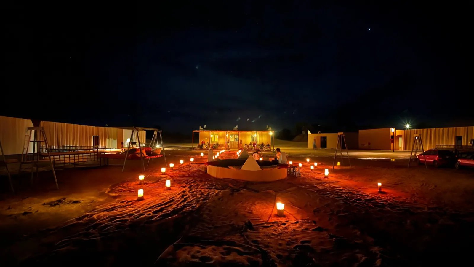 Le campement de nuit, bougies en mandala sur le sable, tentes éclairées