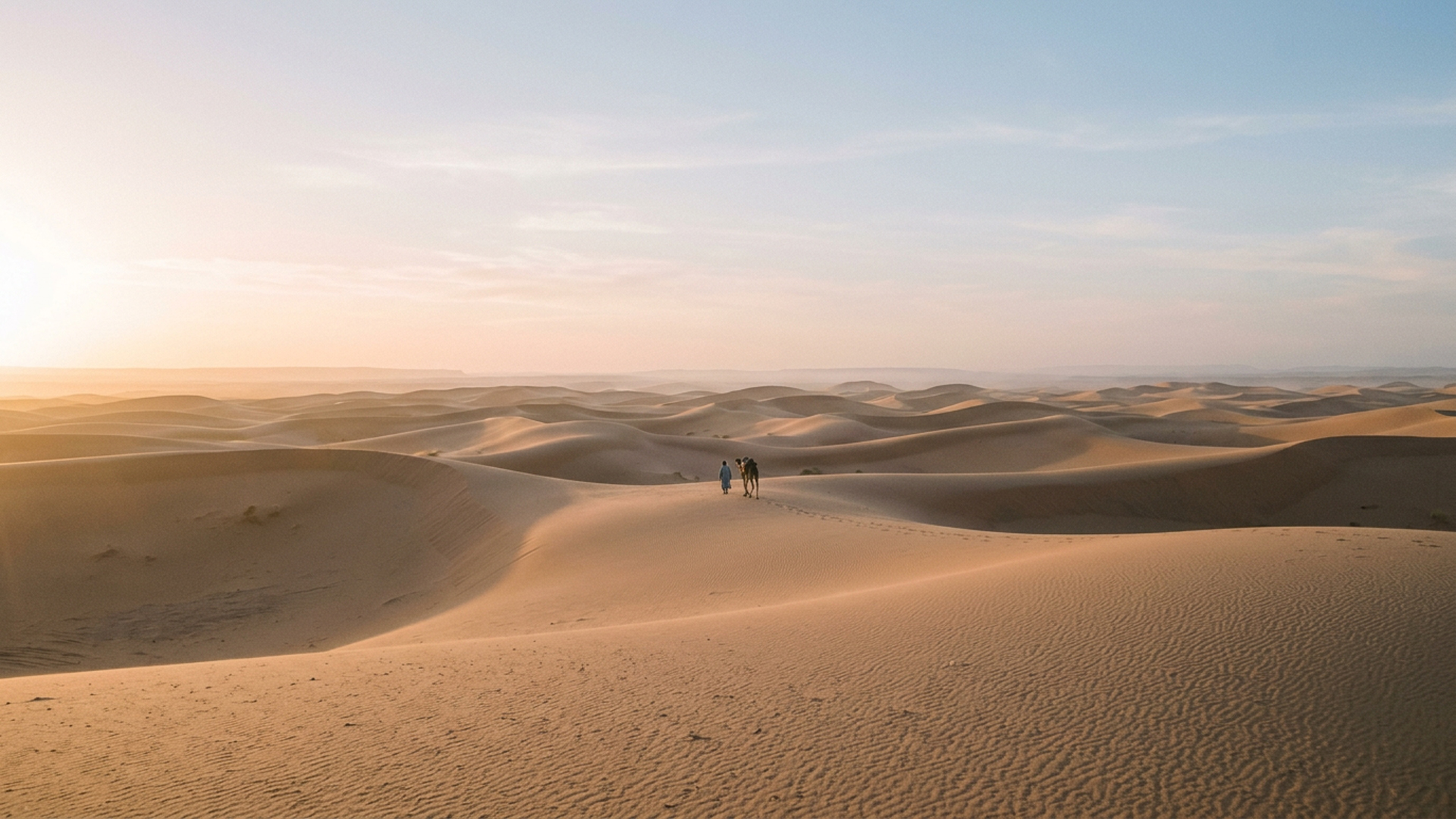 Un homme et son dromadaire au loin sur les dunes dorées, à l'heure dorée